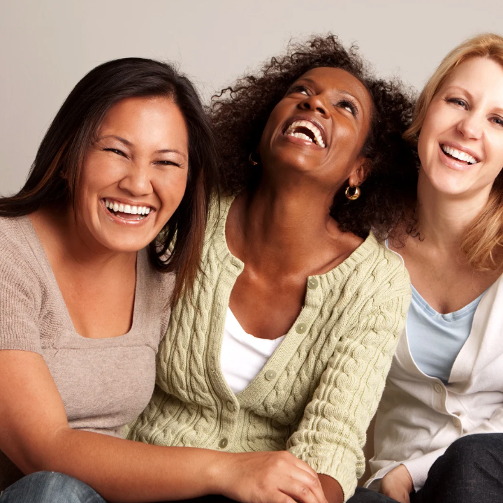 3 women sitting close and laughing