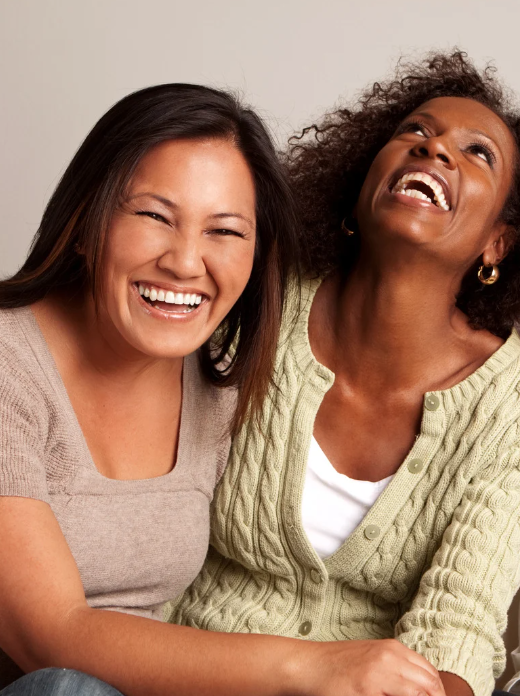 middle aged asian woman and middle african american woman laughing together.