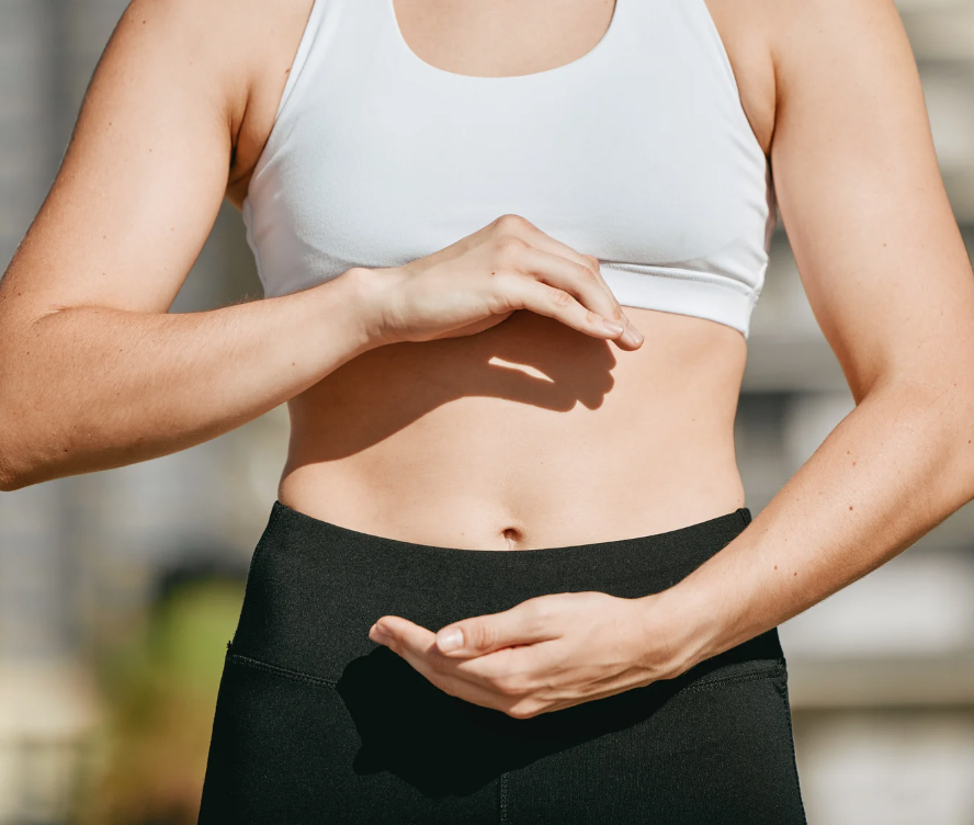 Picture of woman focusing on her midsection. Her face is cut off the picture so the focus is on the stomach area that she is cupping.