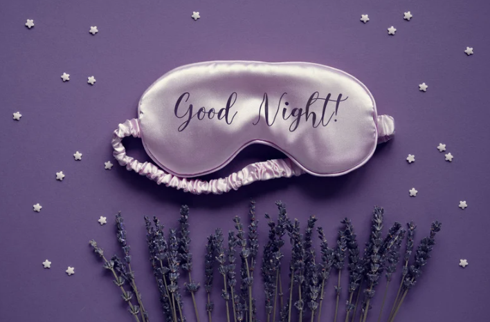 lavender sleep mask that says, "Good Night," purple background, lavender plants at bottom of picture, and fake stars sprinkled throughout the picture
