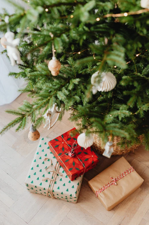 Christmas gifts under a decorated tree with white ornaments and warm lights, symbolizing peace, joy, and mindful holiday preparation.