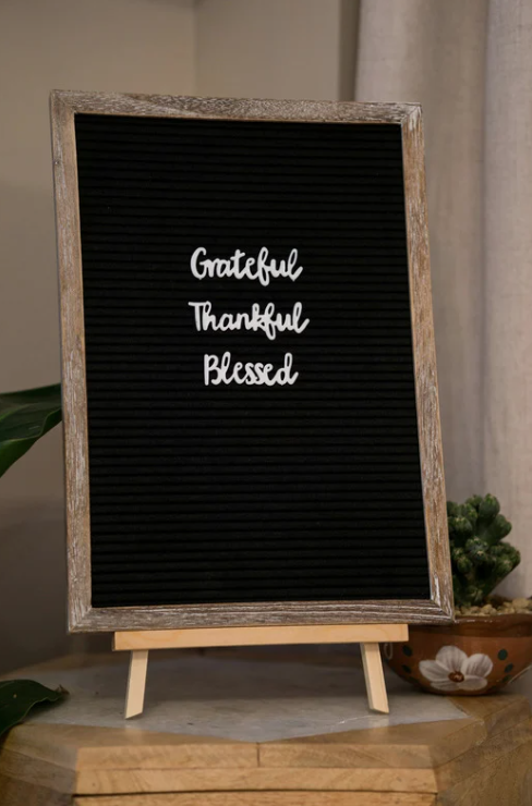 Black letter board on a wooden stand displaying the words “Grateful, Thankful, Blessed.”