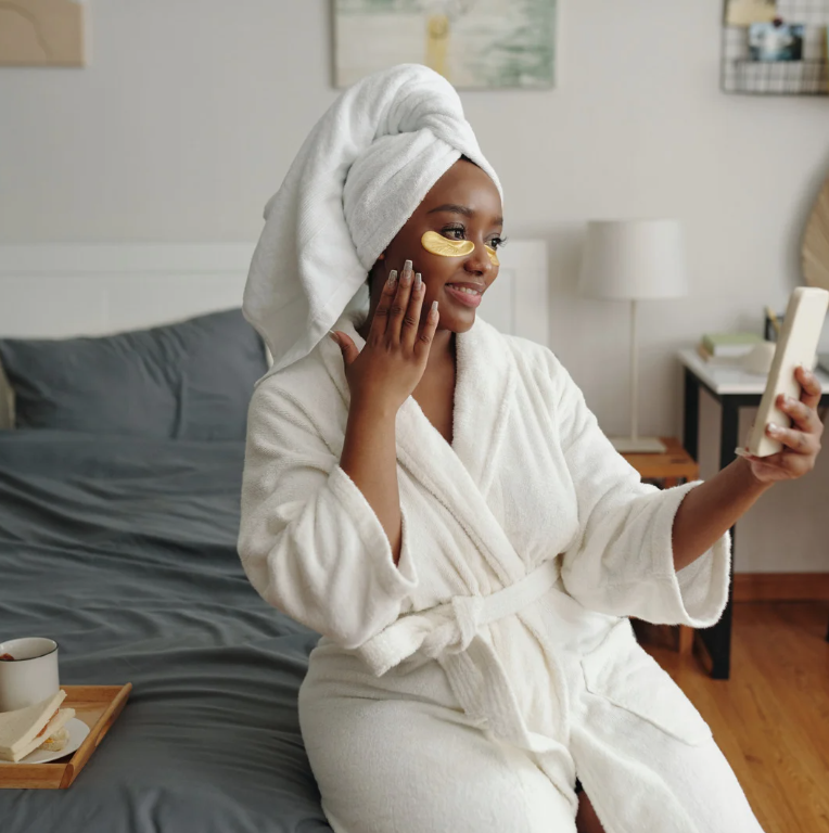 Woman doing nighttime skincare routine at home with robe and eye patches