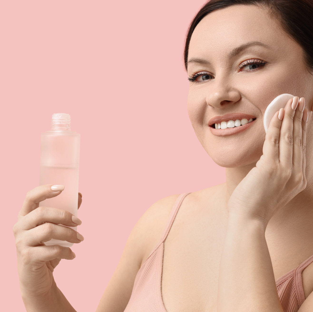 Woman applying a toning essence with a cotton pad as part of a skincare routine for mature skin after cleansing.