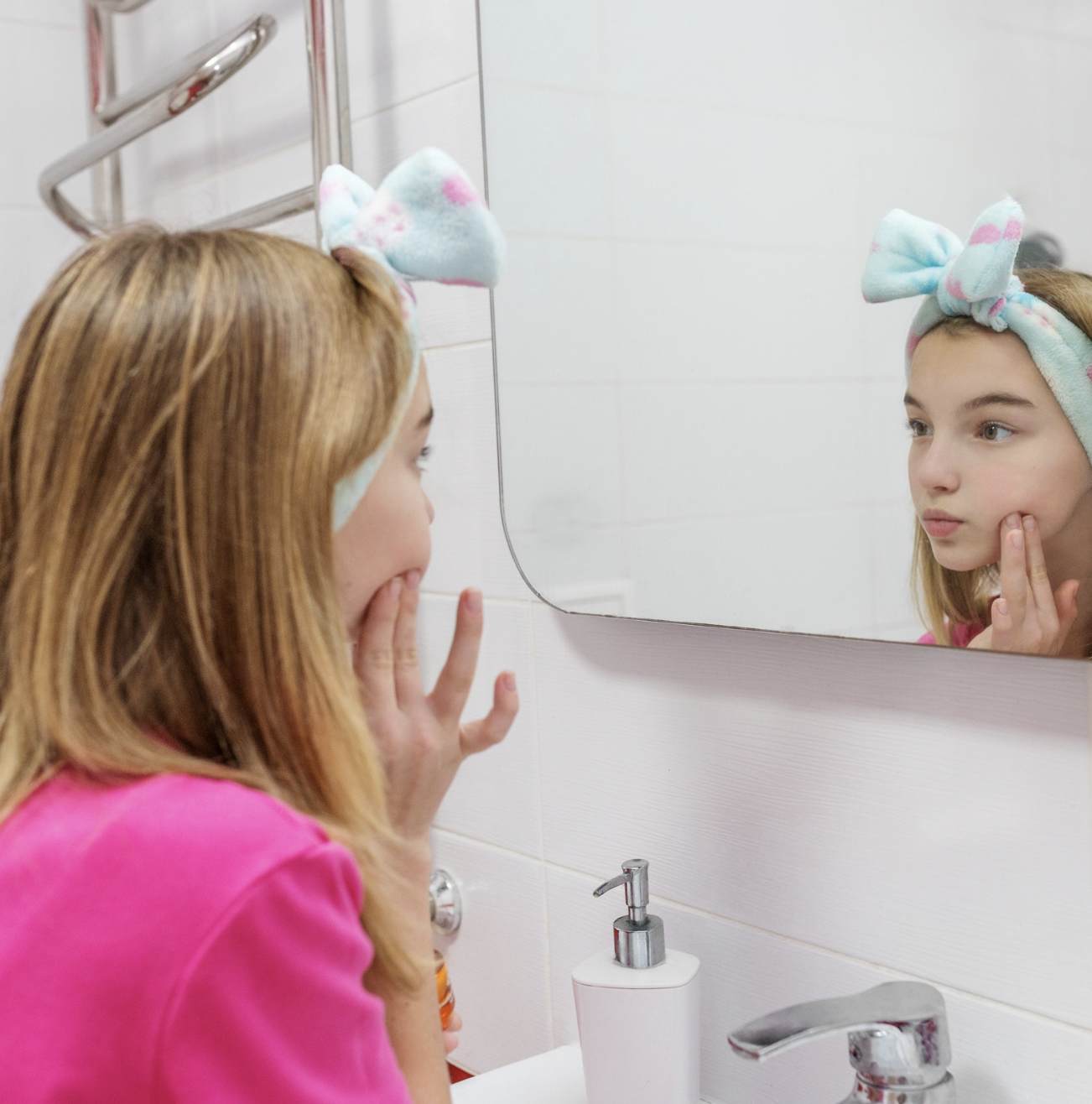 Teen girl looking at her skin in the mirror as part of an acne skincare routine
