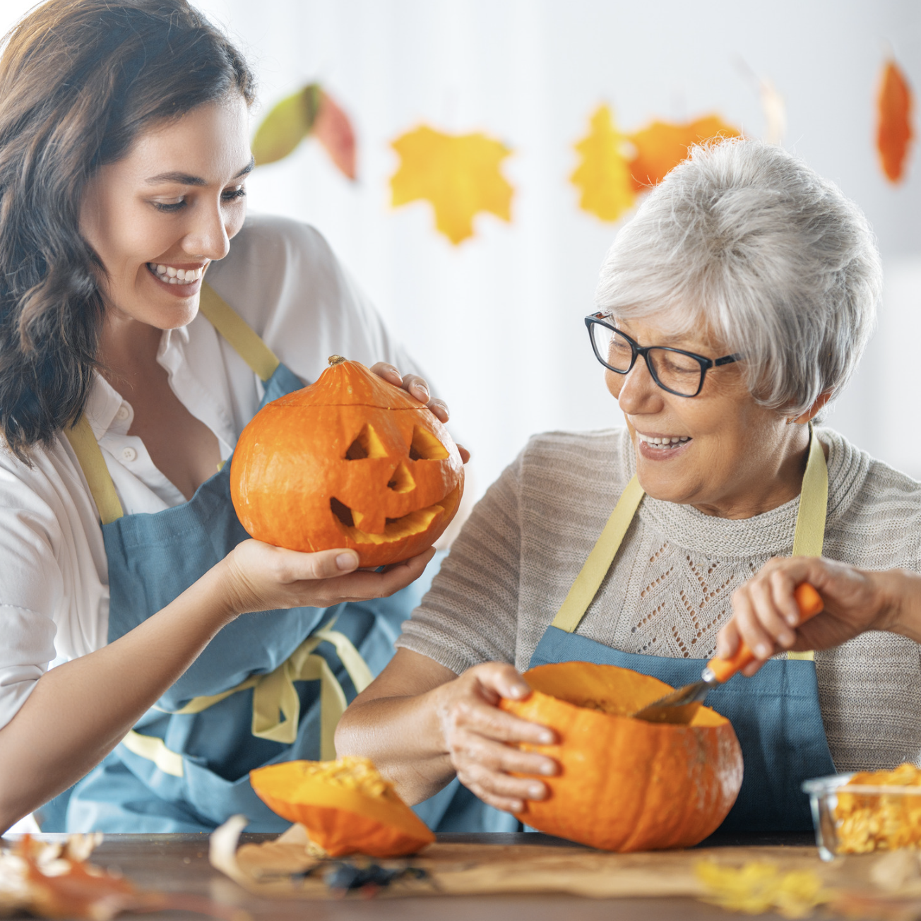 Two women of different generations enjoying Halloween pumpkin carving together.